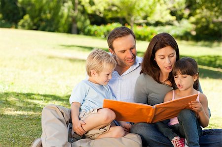 family photos in album - Family looking at their photo album in the park Stock Photo - Budget Royalty-Free & Subscription, Code: 400-05314830