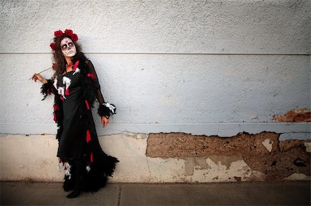 Woman in makeup for Day of the Dead stands alongside a wall with red roses Stock Photo - Budget Royalty-Free & Subscription, Code: 400-05315130