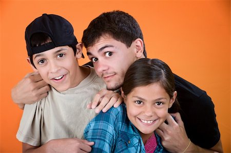 Teen holding and playing with brother and sister on an orange background Stock Photo - Budget Royalty-Free & Subscription, Code: 400-05315150