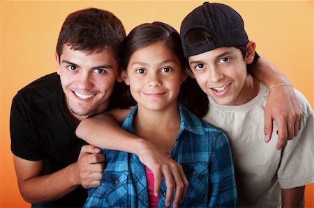 Caring brothers with their sister smiling on orange background Photographie de stock - Aubaine LD & Abonnement, Code: 400-05315152