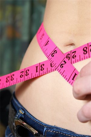A woman measures her waistline to account for her ideal size and fitness. Stock Photo - Budget Royalty-Free & Subscription, Code: 400-05315443