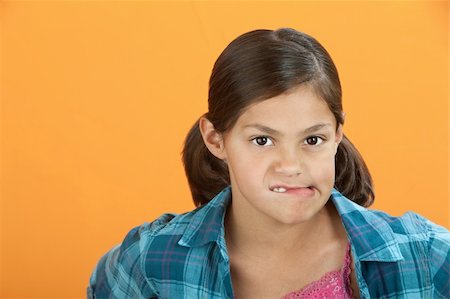 Latina girl on orange background bites her lips Stock Photo - Budget Royalty-Free & Subscription, Code: 400-05317307