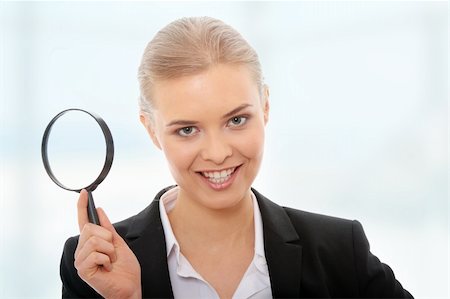 simsearch:400-04554899,k - Young attractive smiling business woman looking into a magnifying glass Stock Photo - Budget Royalty-Free & Subscription, Code: 400-05317566