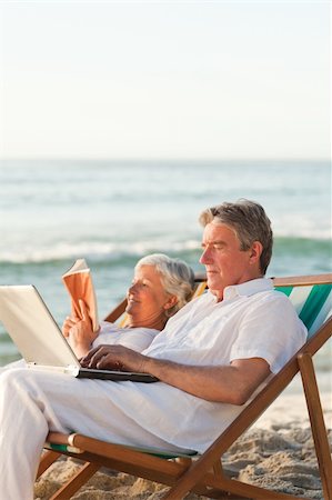 retirement beach deckchair - Woman reading while her husband is working on his laptop Stock Photo - Budget Royalty-Free & Subscription, Code: 400-05318569