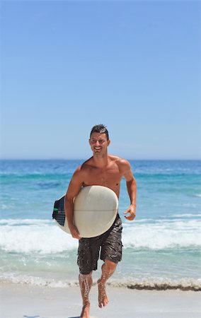 surf board running beach - Man running on the beach with his surfboard Stock Photo - Budget Royalty-Free & Subscription, Code: 400-05318852