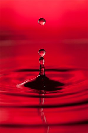 simsearch:400-05123748,k - A red abstract background of a close up of transparent water drops falling in water, making beautifull ripples and flowing waves in the surface and showing the pure energy it creates. Small depth of field. Photographie de stock - Aubaine LD & Abonnement, Code: 400-05311761