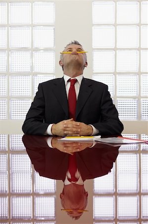 Frustrated mature businessman holding pencil between mouth and nose in office meeting room. Vertical shape, front view, waist up Stock Photo - Budget Royalty-Free & Subscription, Code: 400-05313922