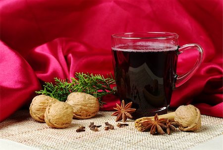 Mulled wine with cinnamon, star anise, walnuts, cloves and a branch of evergreen on mat with red fabric as background (Selective Focus) Stock Photo - Budget Royalty-Free & Subscription, Code: 400-05328662