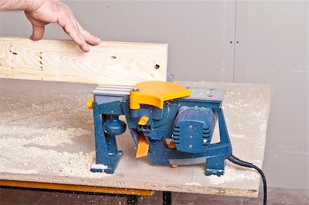 simsearch:400-04856931,k - Close-up of a construction worker's hand and power tool while planing a piece of wood trim for a project. Photographie de stock - Aubaine LD & Abonnement, Code: 400-05329655