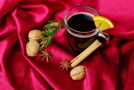 Hot spiced red wine with orange, cinnamon, star anise, walnuts and a branch of evergreen on red fabric (Selective Focus) Stock Photo - Budget Royalty-Free & Subscription, Code: 400-05320189