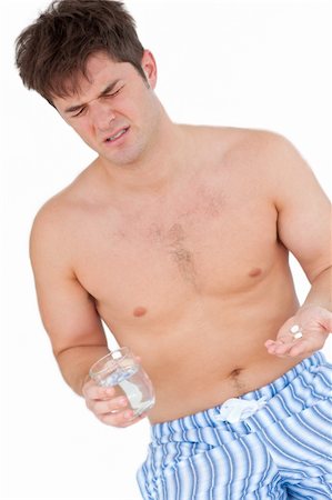 Bare-chested man in pajamas holding pills and a glass of water against a white background Stock Photo - Budget Royalty-Free & Subscription, Code: 400-05320818