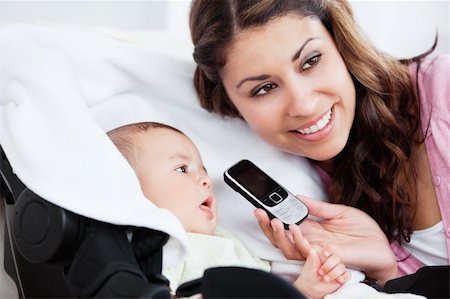 pictures of new born baby rooms - Smiling young mother showing a cellophone to her curious baby at home Foto de stock - Super Valor sin royalties y Suscripción, Código: 400-05320833