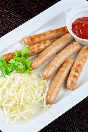 simsearch:400-04295211,k - Grilled sausages with cabbage, greens and tomato sauce on white plate Fotografie stock - Microstock e Abbonamento, Codice: 400-05335066