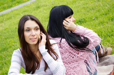 sunny_baby (artist) - Attractive mother and teenage daughter talk on the phone outdoors in a park sitting back to back Foto de stock - Royalty-Free Super Valor e Assinatura, Número: 400-05335740