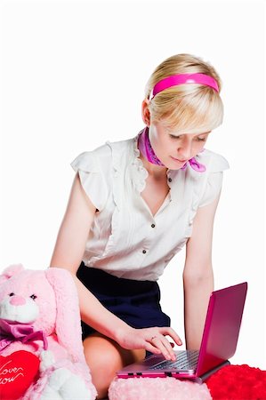 Portrait of beautiful blond girl wearing short skirt and white shoes near pink rabbit working with pink laptop on isolated white background Stockbilder - Microstock & Abonnement, Bildnummer: 400-05335854