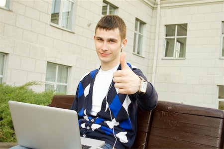 sunny_baby (artist) - Close-up young attractive student studies on a laptop in a college campus. Sitting on the stairs of the building. Thumbs up Foto de stock - Royalty-Free Super Valor e Assinatura, Número: 400-05336682