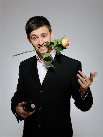 simsearch:400-05294518,k - Handsome romantic young man holding rose flower and vine bottle  prepared for a valentines day. gray background Fotografie stock - Microstock e Abbonamento, Codice: 400-05337202