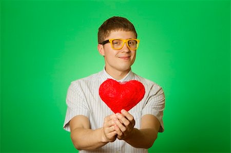 sunny_baby (artist) - Closeup of young attractive man in a shirt, bow tie and glasses smiling holding a red heart Foto de stock - Royalty-Free Super Valor e Assinatura, Número: 400-05337543