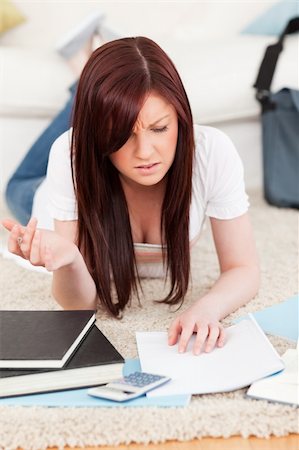 simsearch:400-04829236,k - Upset red-haired female studying for while lying on a carpet in the living room Stock Photo - Budget Royalty-Free & Subscription, Code: 400-05338966