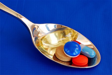 A spoonful of medicine including painkiller and vitamin isolated on blue Stock Photo - Budget Royalty-Free & Subscription, Code: 400-05339677