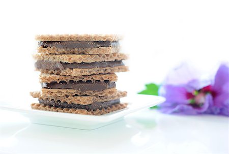 Square wafers with a chocolate-nut filling on a white plate with a purple flower in the background Stock Photo - Budget Royalty-Free & Subscription, Code: 400-05345004