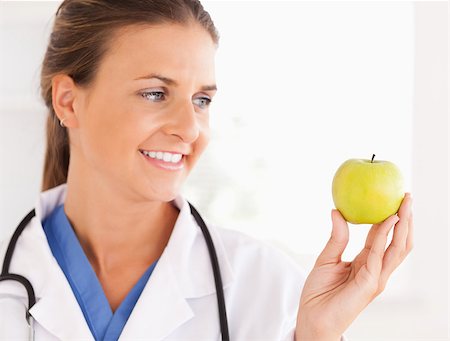 simsearch:400-05728490,k - Close up of a smiling doctor with stethoscope looking at an apple in the surgery Photographie de stock - Aubaine LD & Abonnement, Code: 400-05345150