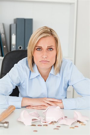 sad women paying bills - Sulking woman sitting in front of an shattered piggy bank looking into camera in her office Stock Photo - Budget Royalty-Free & Subscription, Code: 400-05345304