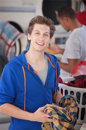 simsearch:400-05347604,k - Handsome man folds a plaid shirt in the laundromat Stockbilder - Microstock & Abonnement, Bildnummer: 400-05347600