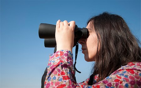 simsearch:400-04632747,k - Young woman using binoculars. On blue sky background Fotografie stock - Microstock e Abbonamento, Codice: 400-05342008