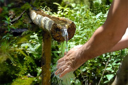 fresh spring drinking water - man washing his hands by spring water under wooden gutter over green natural background Stock Photo - Budget Royalty-Free & Subscription, Code: 400-05343251