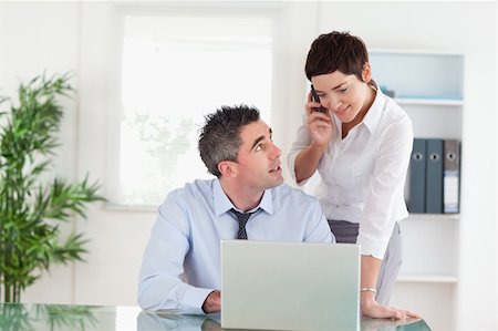 Businesswoman making a phone call while her colleague is working on a laptop in an office Stock Photo - Budget Royalty-Free & Subscription, Code: 400-05354003