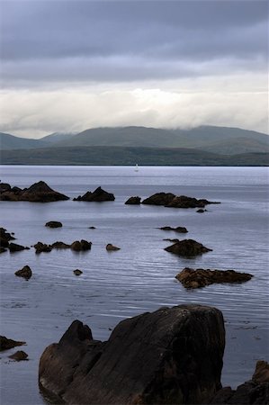 simsearch:400-05360154,k - scenic view in kerry ireland of lone yacht sailing in  rocks and sea with mountains against a beautiful cloudy sky Stock Photo - Budget Royalty-Free & Subscription, Code: 400-05354125