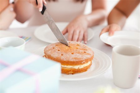 someone cutting cake - Cute Woman sitting at a table cutting a cake in a kitchen Stock Photo - Budget Royalty-Free & Subscription, Code: 400-05354192
