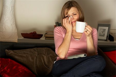 sad woman sitting alone on couch - Woman Relaxing With Cup Of Coffee Watching Television Stock Photo - Budget Royalty-Free & Subscription, Code: 400-05354646