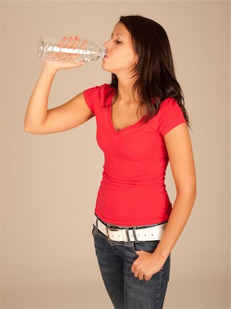 attractive young woman in red t-shirt and jeans drinking bottled water Stock Photo - Budget Royalty-Free & Subscription, Code: 400-05356605