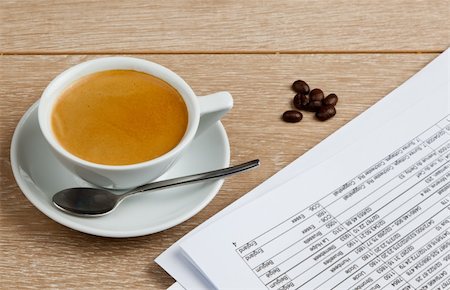 A cup of coffee in a white porcelain cup with a small pile of coffee beans and some office papers Stock Photo - Budget Royalty-Free & Subscription, Code: 400-05356754