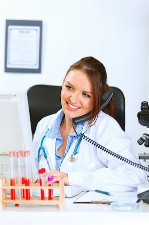 simsearch:400-04925813,k - Smiling medical doctor woman talking on phone and looking in monitor Stock Photo - Budget Royalty-Free & Subscription, Code: 400-05356800