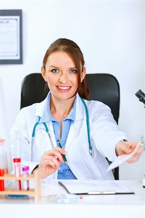 simsearch:400-04390415,k - Smiling medical doctor woman sitting at table and giving medical prescription Stock Photo - Budget Royalty-Free & Subscription, Code: 400-05356801