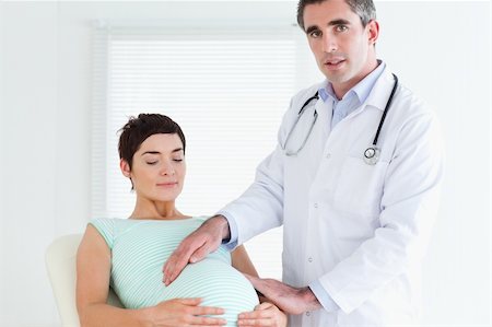 Male Doctor examining a pregnant woman's tummy in a room Stock Photo - Budget Royalty-Free & Subscription, Code: 400-05357226