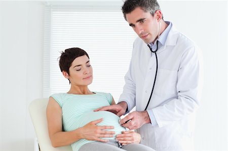 Male Doctor listening into the belly with a stethoscope in a room Stock Photo - Budget Royalty-Free & Subscription, Code: 400-05357229