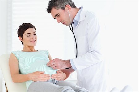 Doctor listening into the woman's tummy with a stethoscope in a room Stock Photo - Budget Royalty-Free & Subscription, Code: 400-05357232