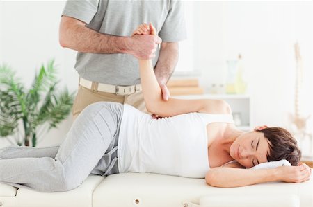 A chiropractor stretches a woman's arm in his surgery Stockbilder - Microstock & Abonnement, Bildnummer: 400-05357464
