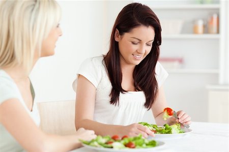 simsearch:400-05357733,k - Portrait of beautiful Women eating salad in a kitchen Fotografie stock - Microstock e Abbonamento, Codice: 400-05357653