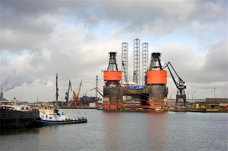 doca seca - The dismantling of an oil rig at a dry dock in the midst of a busy commercial harbor Foto de stock - Royalty-Free Super Valor e Assinatura, Número: 400-05358002