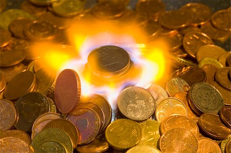 A glowing red hot coin in front of the blue flames of burning natural gas, a metaphor of wasting energy, not only bad for the environment, but also a waste of money Photographie de stock - Aubaine LD & Abonnement, Code: 400-05358038