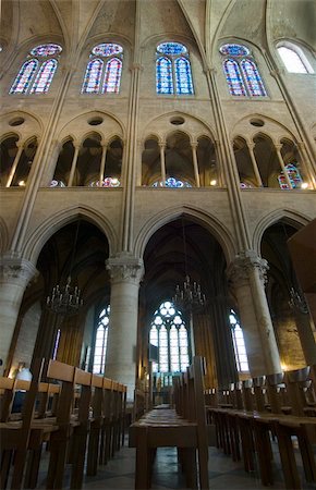 paris churches stained glass - The pews and inner facade of the Notre Dame in Paris, France, with its columns, arches, chandeliers and stained glass windows. Stock Photo - Budget Royalty-Free & Subscription, Code: 400-05358065