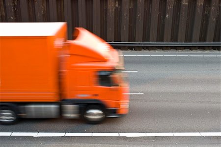 A multiple lane motorway, with lines and the asphalt, on which an orange truck drives past Stock Photo - Budget Royalty-Free & Subscription, Code: 400-05358200