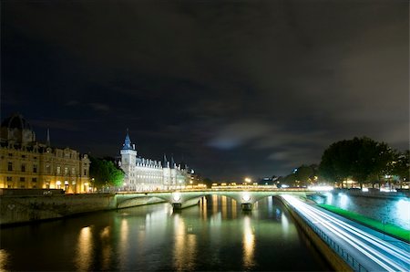 simsearch:400-05358650,k - Bridges over the River Seine in Paris, with the Conciergerie on the Ile de la Cite nicely lit. A patch of clouds is lit with a lightbeam from below, just above the horizon Stock Photo - Budget Royalty-Free & Subscription, Code: 400-05358650
