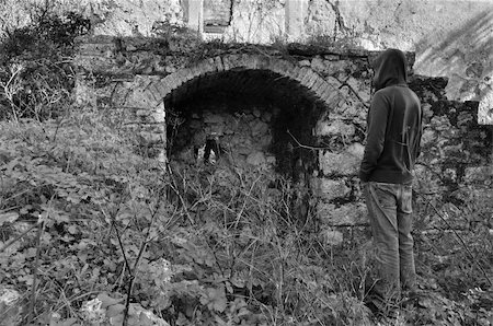 simsearch:400-05352563,k - Overgrown plants and hooded man next to arched recess of rural ruin. Fotografie stock - Microstock e Abbonamento, Codice: 400-05352476
