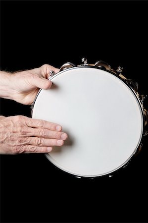 A tambourine being played by hands isolated against a black background in the vertical format. Stock Photo - Budget Royalty-Free & Subscription, Code: 400-05353353